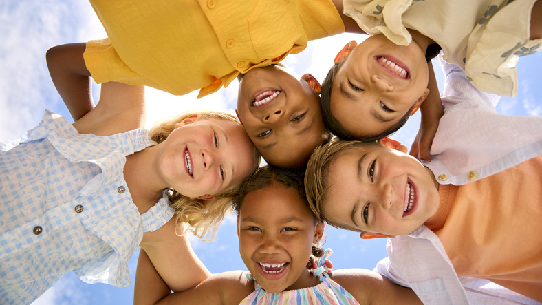 group of children smiling while looking face down at the camera