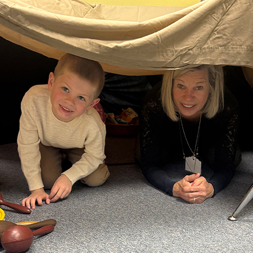 image of young child and female adult hiding under a table, smiling